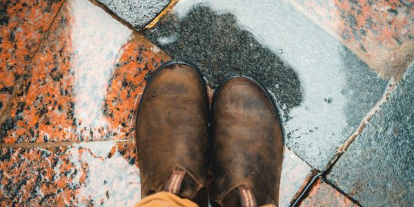 A pair of running shoes and a water bottle on the floor.