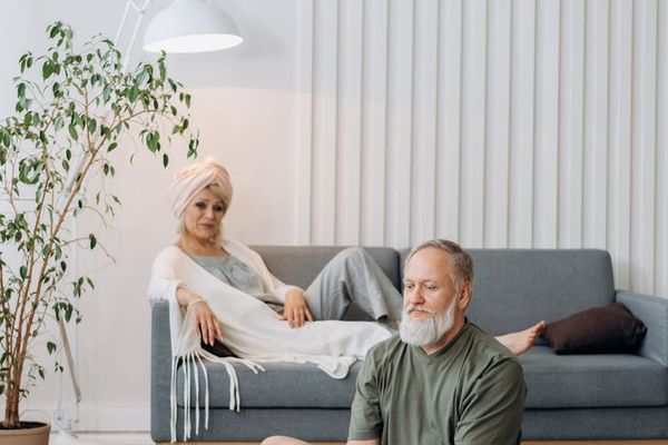 Man stretching on a yoga mat in a well-lit room.